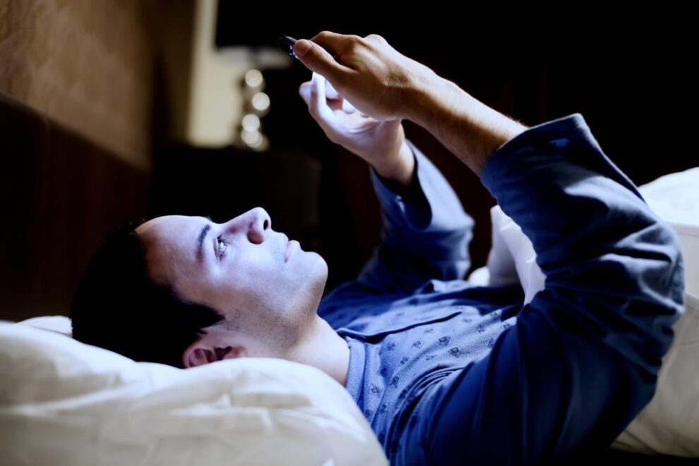 Man in bed looking at his phone screen